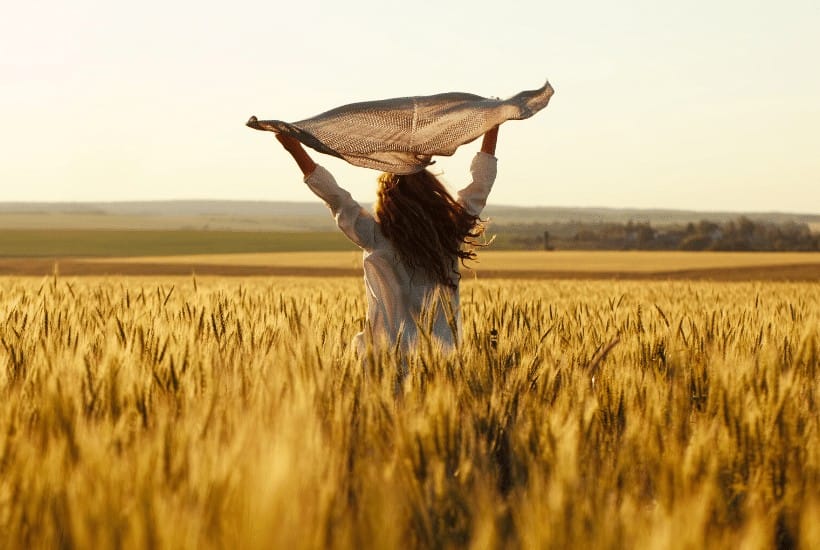 an image of a woman jumping in the air with her arms spread wide 27 Bible Verses About Overcoming Guilt as a Christian featured