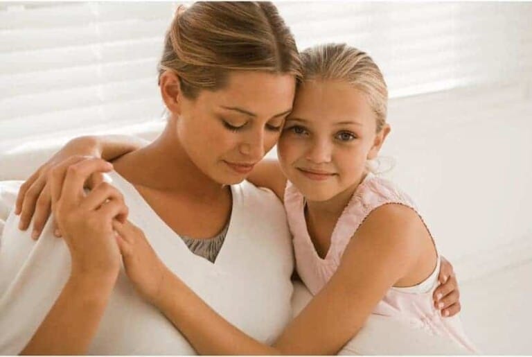 an image of a mother and small child sitting on a couch with their arms around one another with featured image for When Mother's Day is Hard