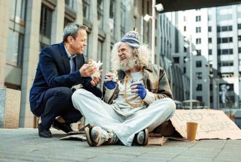 an image of a man approaching a homeless person person with something to eat. featured image for How to Show Acts of Kindness in the Midst of Chaos
