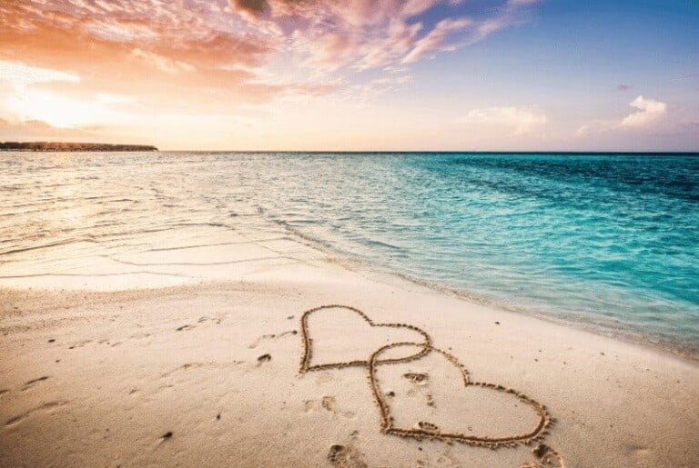 an image of a beach scene to two hearts carved in the sand featured image for 9 Ways to Guard Your Heart Biblically