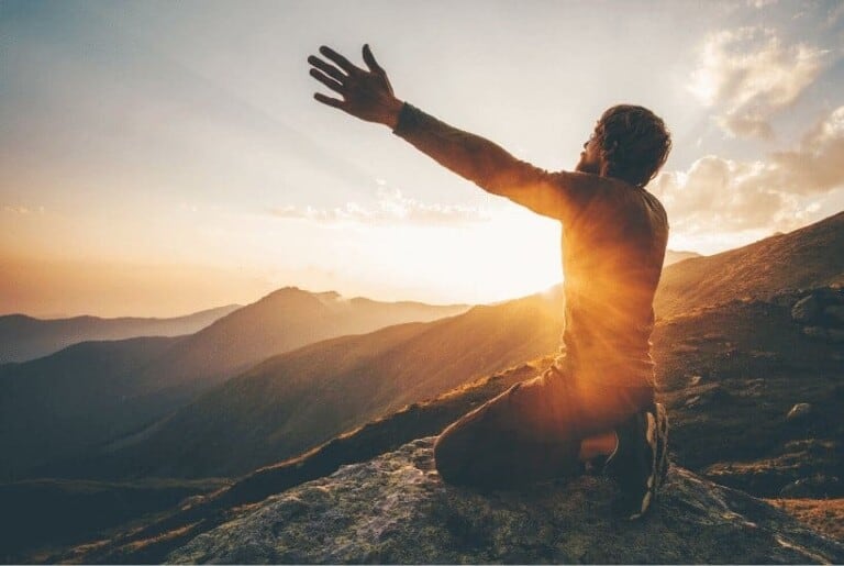 an image of a man on his knees with arms raised high with sunset in the background featured image for God Answers Prayers 3 Real Life Examples Of His Blessings