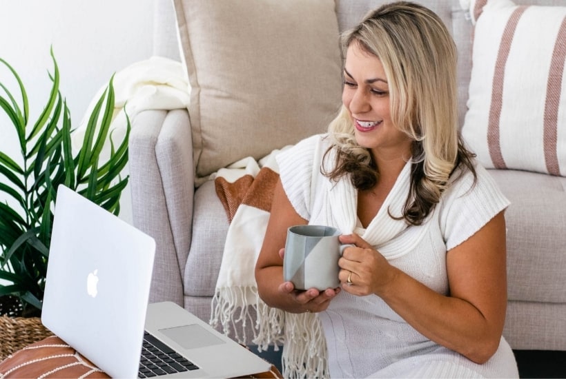 a woman sitting on a white couch drinking from a cup with a white opened laptop in front of her featured image for Resources for Christian Women