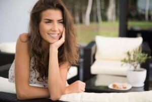 a woman leaning against a counter with her hand under in her chin smiling featured image for Finding Peace and Joy after Loss in 5 Helpful Ways