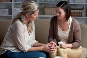 2 women sitting on a tan couch talking and drinking coffee featured image for Processing Grief with Hope Is Hope Even Possible?