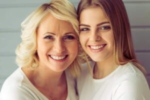 a teenage daughter with her arms around her mother both are smiling featured image for 6 Hopeful Ways Of Learning To Let Go Of The Loss Of A Child